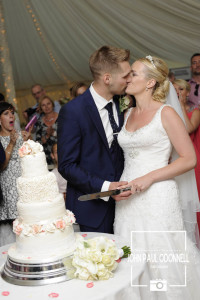 Bride and Groom kissing whilst cutting the cake